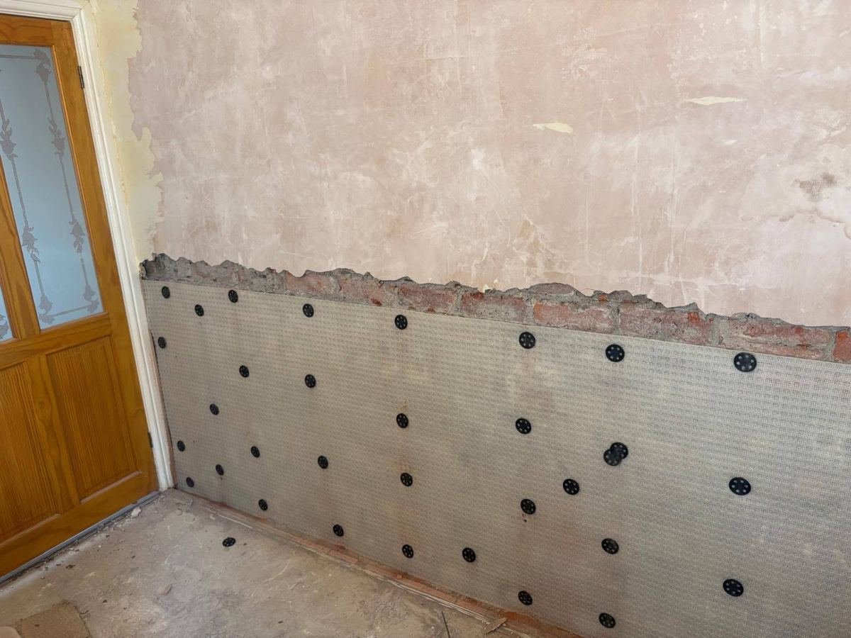Damp proof membrane fixed to the lower wall beside a glazed door