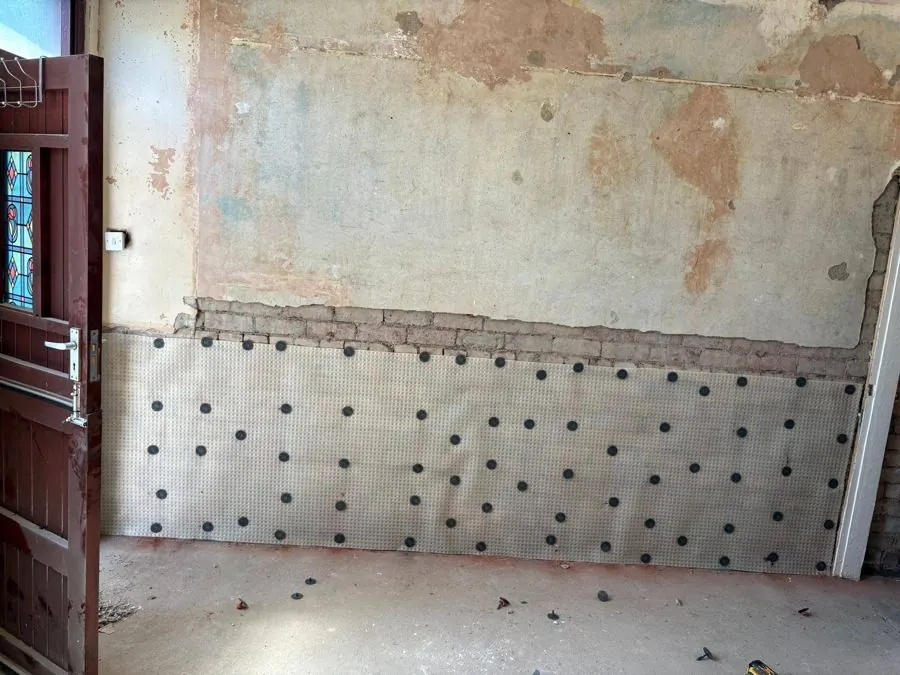 Damp proof membrane system installed across a treated wall