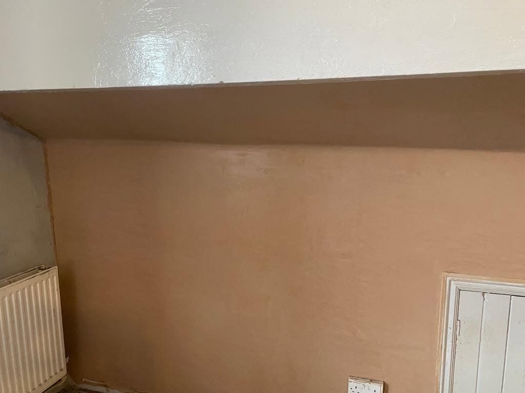 A freshly skimmed wall and sloping ceiling in a loft bedroom
