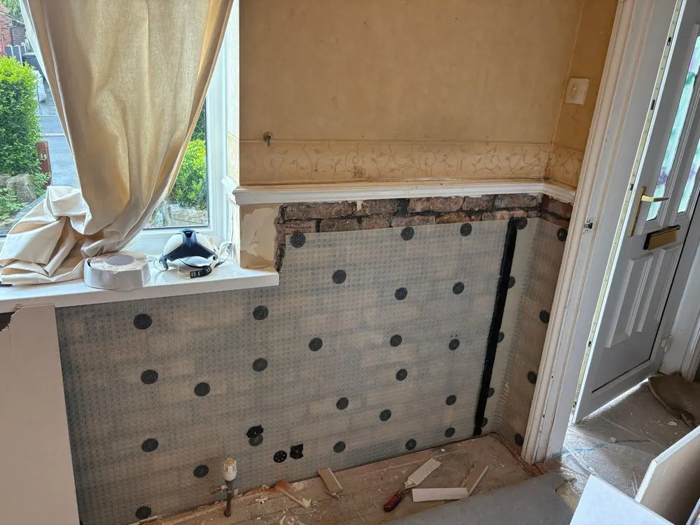 Meshed damp proof membrane fixed below a window and round to a front door, before replastering