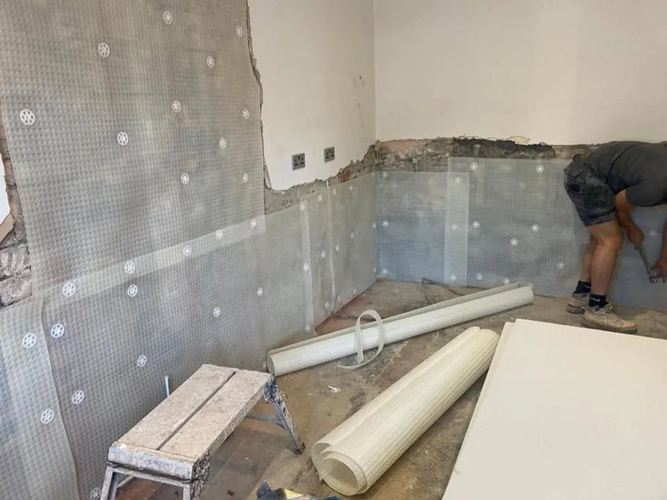 A meshed membrane being fixed to the lower walls of a room after damp treatment
