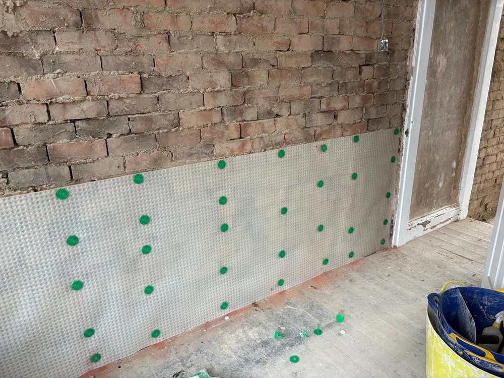 Meshed damp proof membrane fixed across the lower wall with the treated brickwork still exposed above