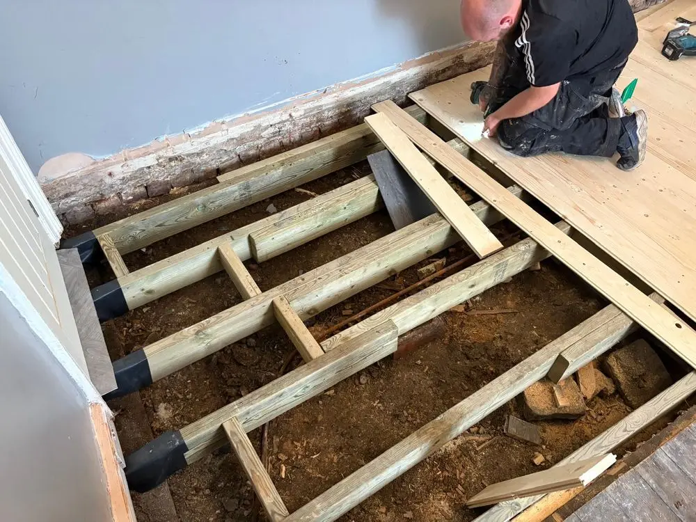 New floor joists and boards being fitted, with the joist ends wrapped where they meet the wall