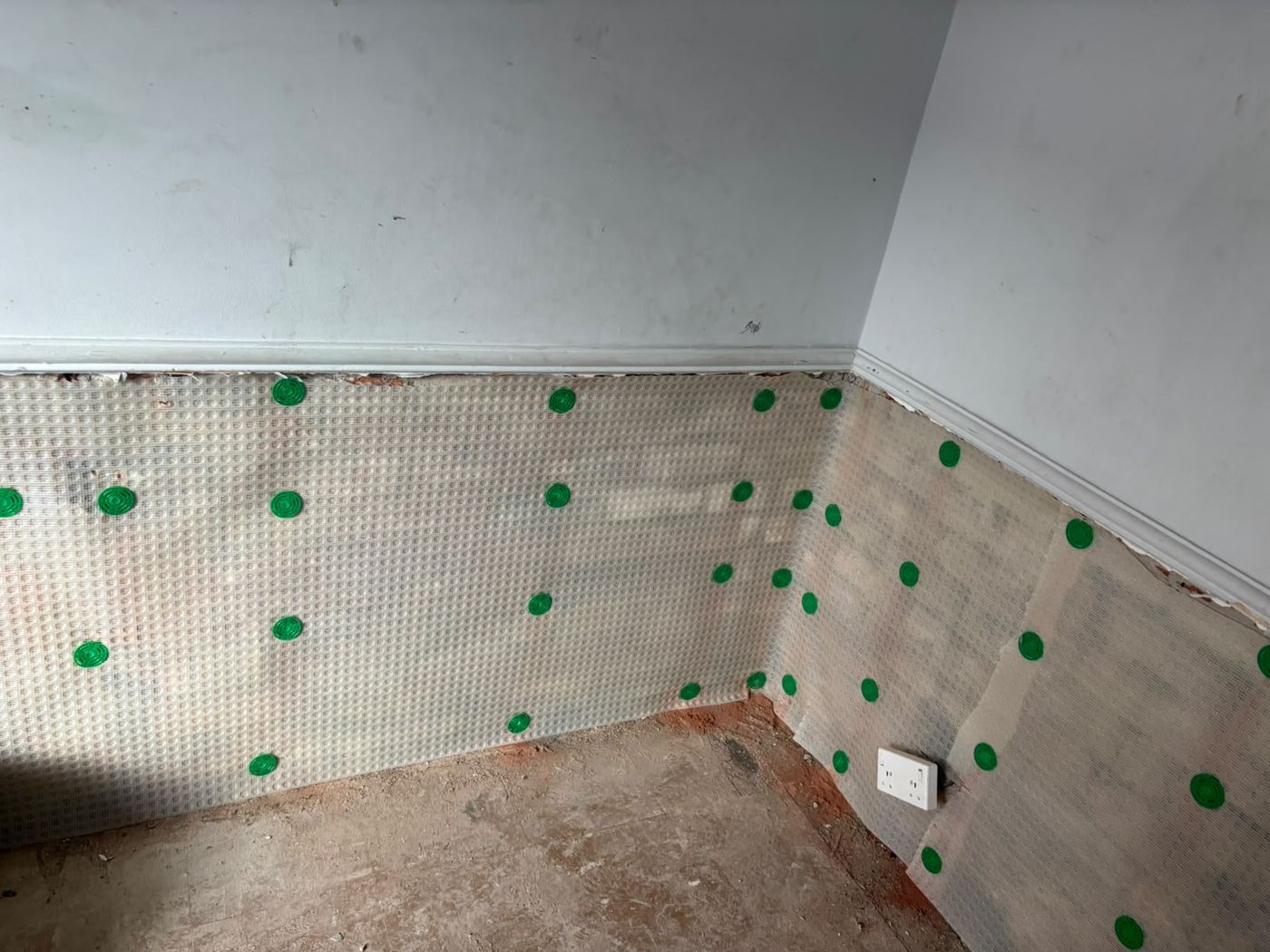 Meshed damp proof membrane fixed across two walls of a room after damp treatment