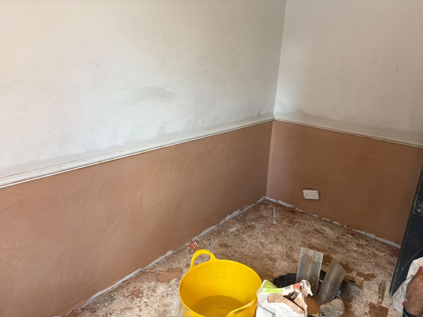 A room corner replastered to a smooth finish below the picture rail