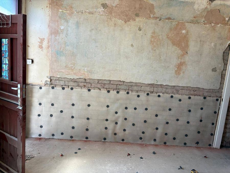Damp proof membrane system installed across a treated wall