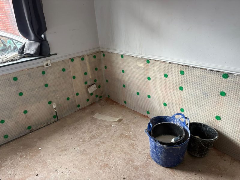 Meshed damp proof membrane fixed across two walls of a room during a damp treatment